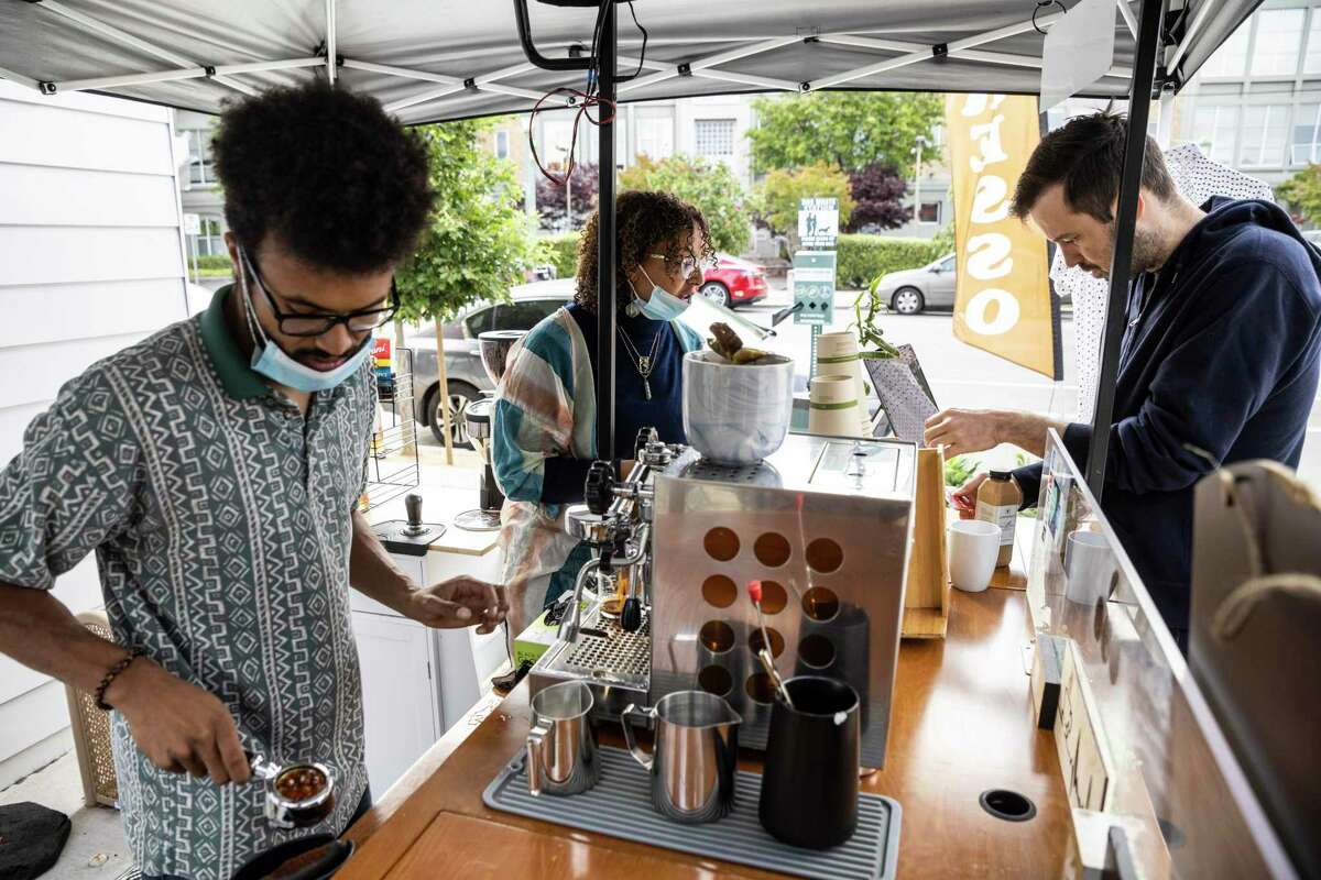 Justice Chambers (left) works on an espresso machine as partner Jenna Garrett takes an order from neighbor Walter Howell at their Soul Blends Coffee Roasters pop-up cart.