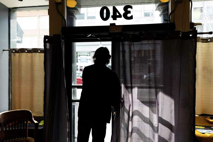 Gino Gentile, seen from behind, looks out the window of his shop, Anthony’s Shoe Service.