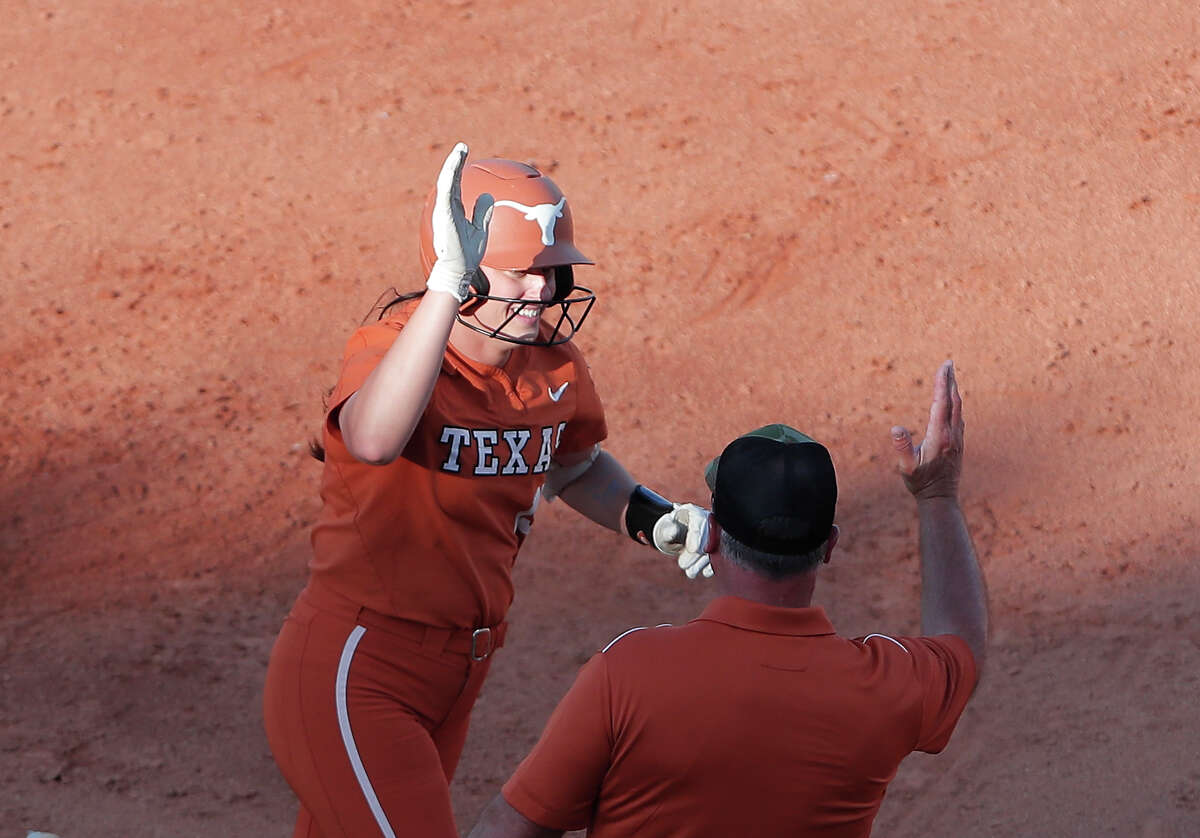 Texas' Courtney Day, left, celebrates after hitting home run during the second inning of an NCAA softball Women's College World Series game against Oklahoma State on Monday, June 6, 2022, in Oklahoma City. (AP Photo/Alonzo Adams)