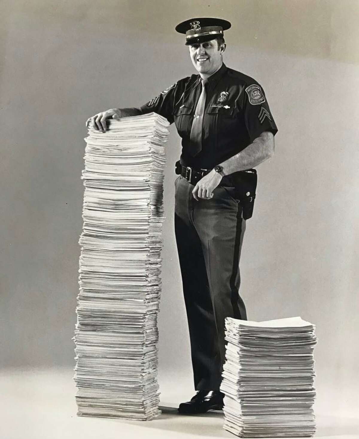 Michigan State Police Sgt. Gordon Gotts, president of the 1,460-member Michigan State Police Troopers Association, with 166,000 signatures of Michigan registered voters who have signed a petition to put the issue of collective bargaining for state troopers and sergeants on the 1978 General Election Ballot. Gotts, who stands at 6 foot 4 inches, is shown with a stack of signed petitions. January 1978
