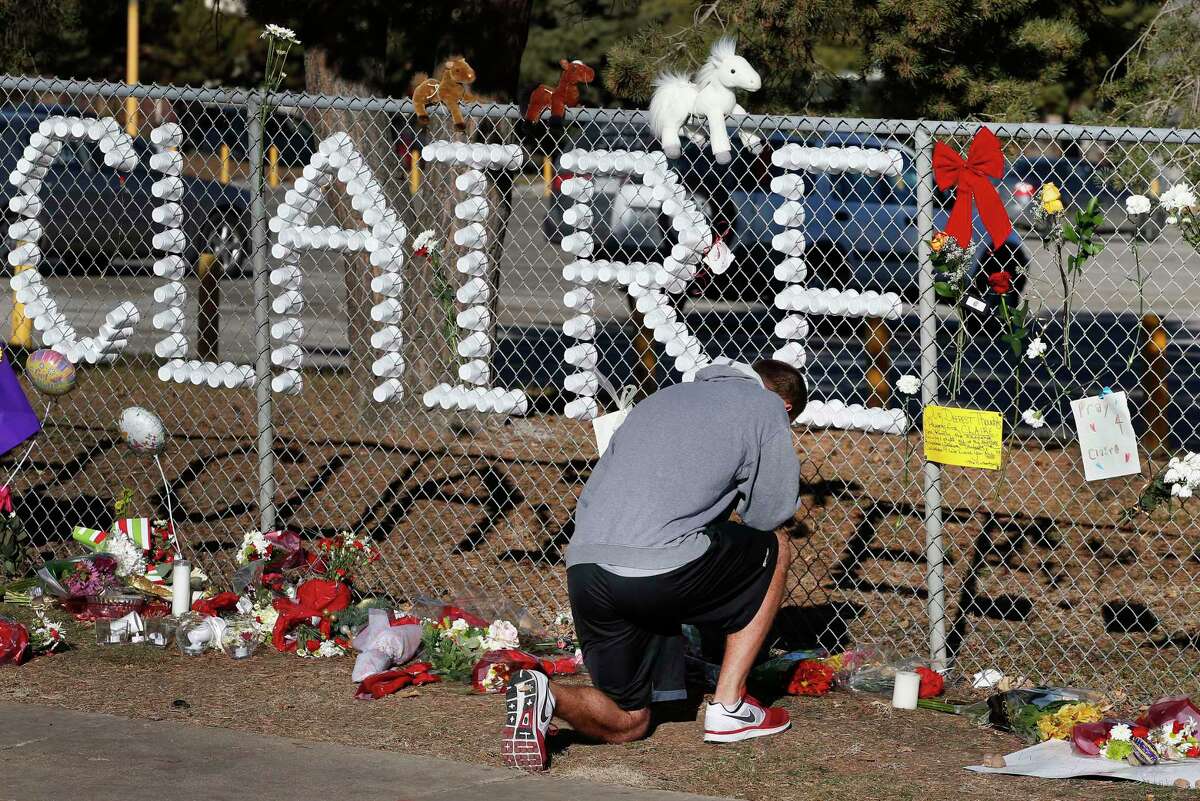 Parker Semin, a 2011 Arapahoe High School graduate, prays at a makeshift memorial bearing the name of wounded student Claire Davis, who was shot by a classmate during school three days earlier in an attack, in front of Arapahoe High School in Centennial, Colo., Monday, Dec. 16, 2013.