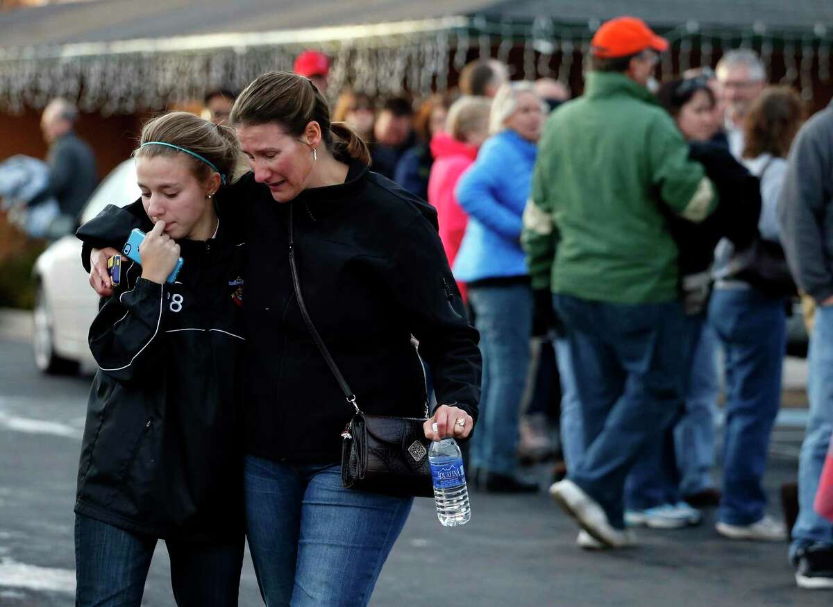 A parent picks up her daughter at a church where students from nearby Arapahoe High School were evacuated to after a shooting on the Centennial, Colo., campus Friday, Dec. 13, 2013.