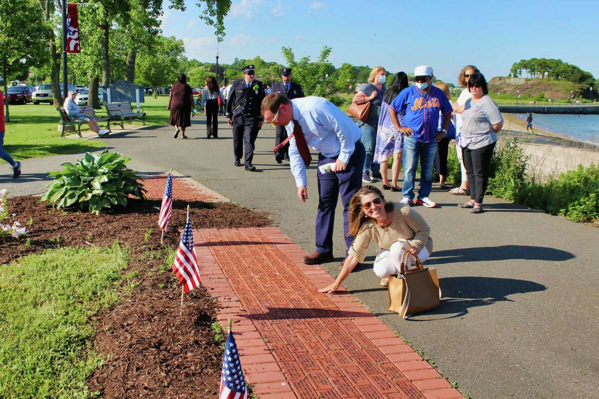 West Haven resident Kim-Marie Mullin touches the Walk of Honor brick she purchased for her father, John J. Mullin, a Navy veteran who served as a torpedoman’s mate in Vietnam. Behind Mullin, Councilman Steven J. Johnstone, R-10, searches for the brick he purchased for his grandfather, World War II Army Staff Sgt. Frederick H. Johnstone. Each $75 brick has a personalized message engraved in charcoal lettering.