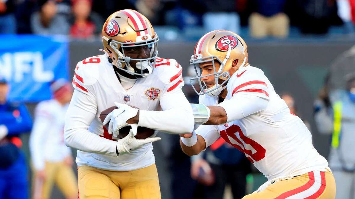 Jimmy Garoppolo, desde la derecha, pasa el balón a Dibo Samuel el 12 de diciembre de 2021 en Cincinnati, Ohio. 