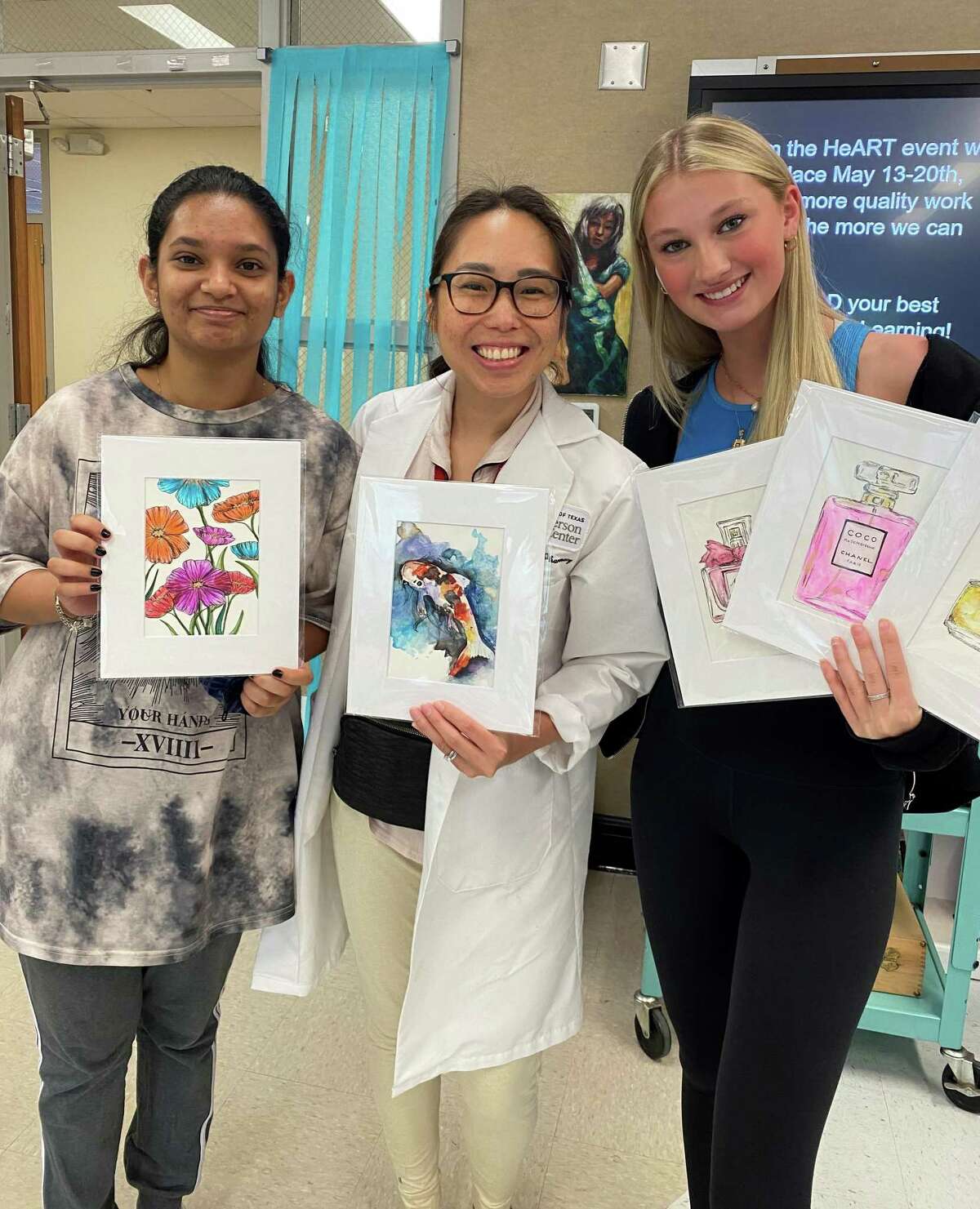 Memorial High School teacher Annie Huynh and two students show off their artworks from the “from the heART” fundraiser.