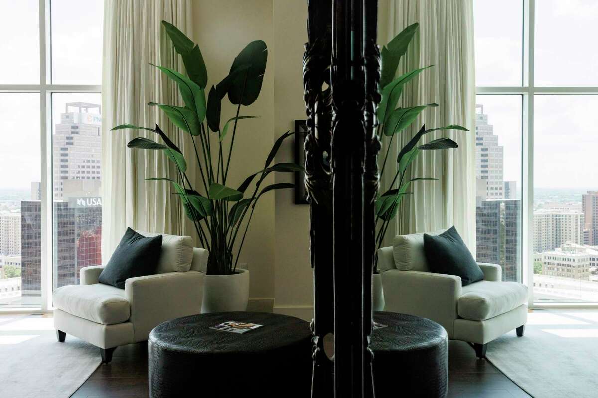 The owner’s suite in Charlie Amato’s two-story penthouse features white and black furniture with pops of color from large plants.
