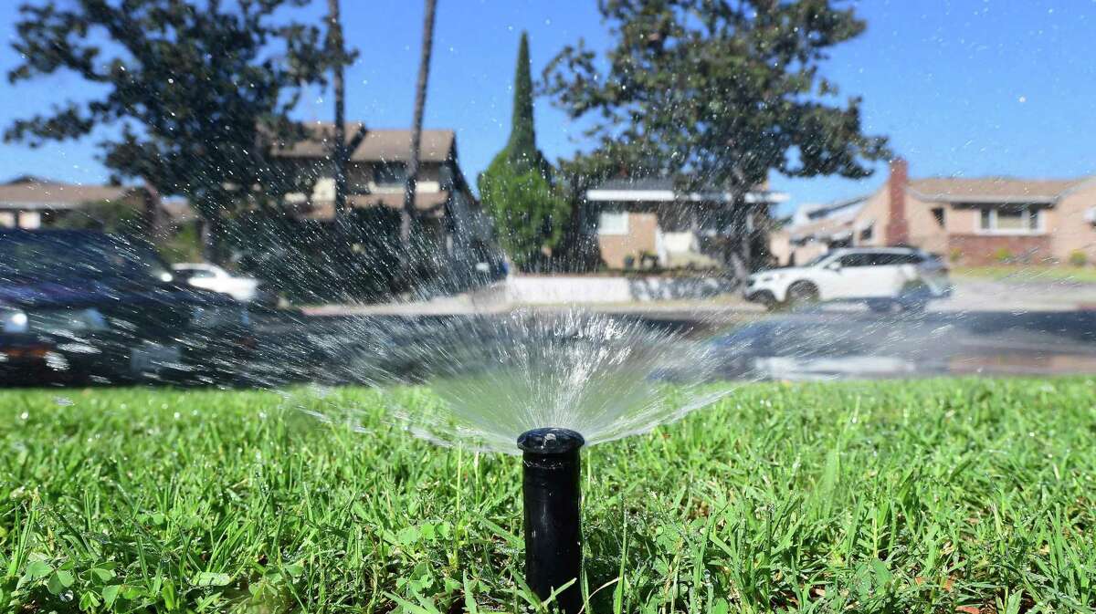 A sprinkler waters grass in Alhambra, California. California cities and towns are lagging in state-set conservation goals.