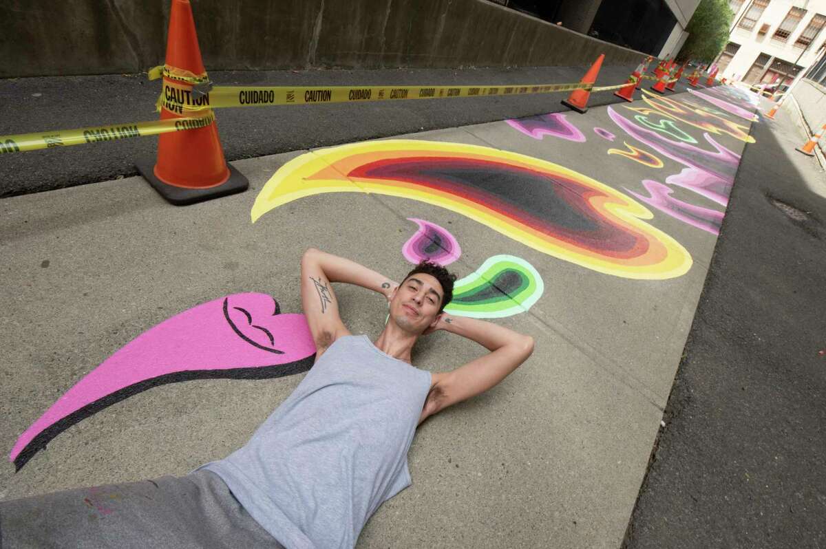 Local artist Eugene O'Neill is seen with his mural "Meet Me in the Middle" which he painted on the sidewalk along William Street Tuesday, June 7, 2022 in Albany, N.Y. The image at the left is called Joy the Pink Paint Puddle.