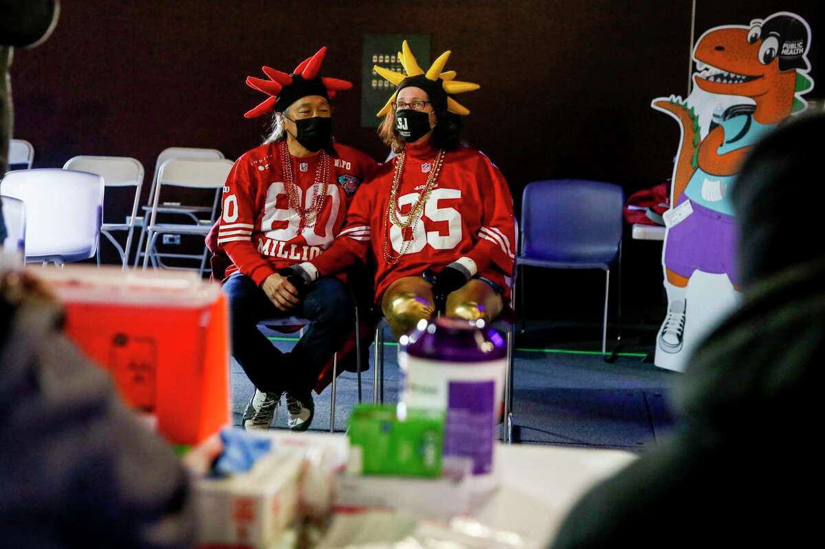 Linda Kahn waits with her husband Jeff Lew after he received his booster during a vaccination clinic held by the Santa Clara County Public Health Department at the Children’s Discovery Museum in San Jose on Jan. 2, 2022.