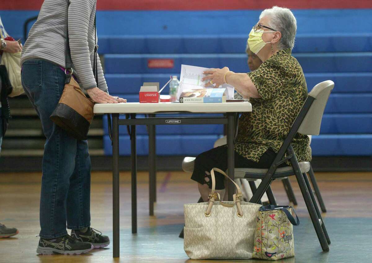 Angela Hylenski, of Danbury, checks in a voter at the Danbury War Memorial gymnasium Tuesday, where residents were deciding on a $208 million borrowing package to meet the city's growing school enrollment.