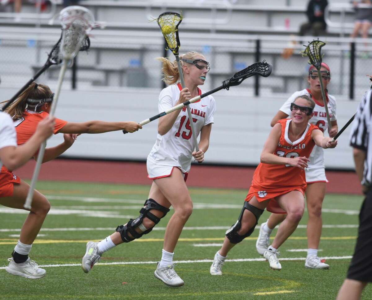 New Canaan’s Caitlin Tully (15) carries the ball between Ridgefield defenders Jacqueline Lehaney, right, and Aerin Krys during the CIAC Girls Lacrosse Class L semifinals on Tuesday, June 7, 2022 in Greenwich, Conn.