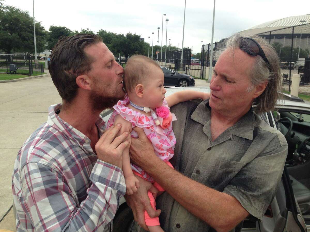 Trevor Cook, left, kisses his daughter, Lieah, on the head, with his father, Cary, by his side. After Trevor’s death in 2018, Cary vowed to build a home for Lieah and her mom, Lissethe, on a 50-acre tract of land he owns so he can watch his granddaughter grow up.