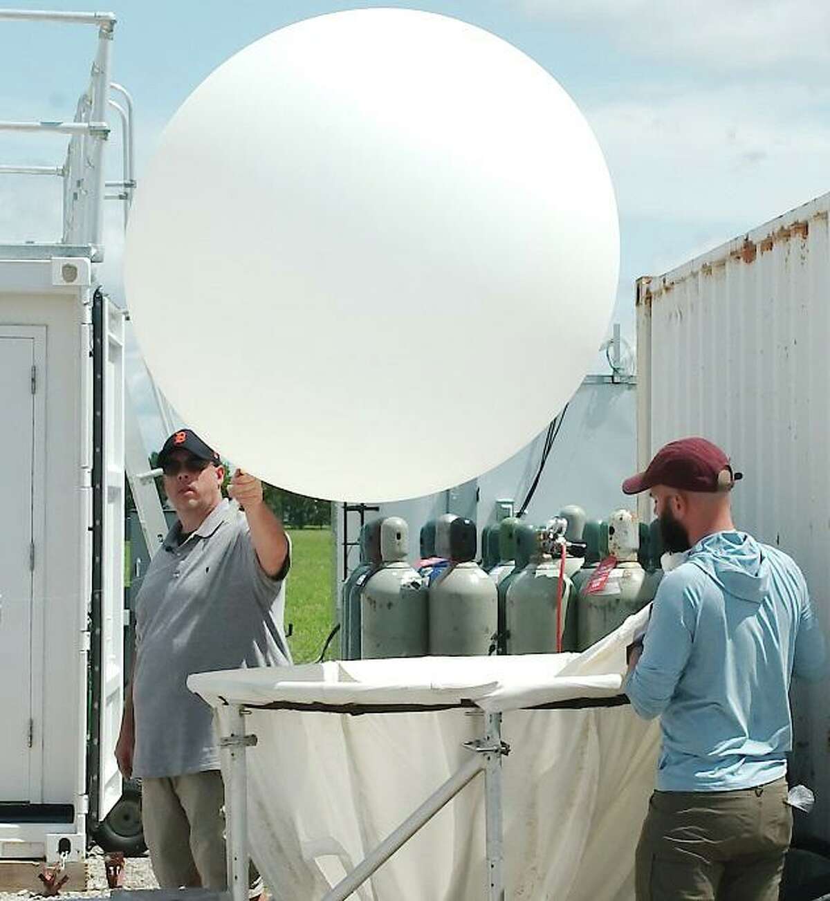 Atmospheric Radiation Measurement Mobile Facility technicians David Oaks and Mark Spychala inflate a weather balloon with helium that will be used to gather atmospheric data at the Department of Energy’s ARM facility at La Porte Municipal Airport.