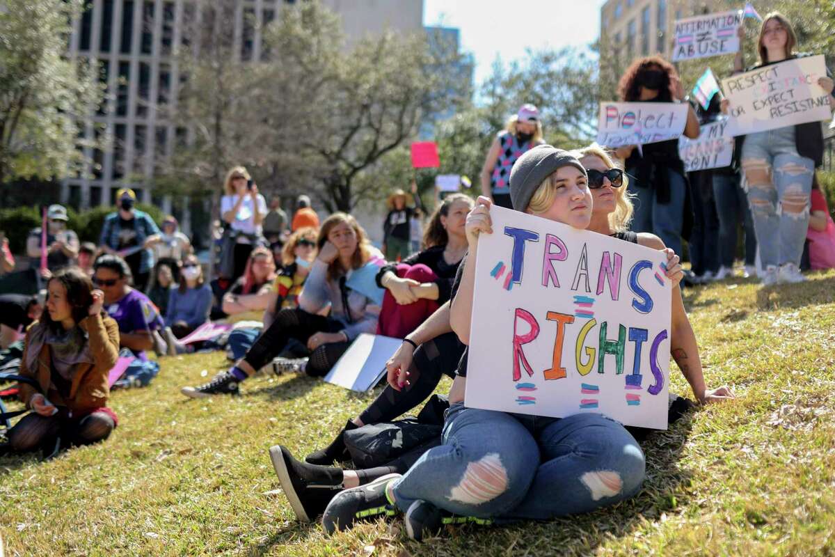 J.J. Holsinger, 12, leans against Bex Holsinger as they listen to speakers during a rally for transgender rights held outside the Texas Governors Mansion in Austin, Texas, on March 13, 2022. LGBTQ+ advocates the rally to protest Gov. Greg Abbott's directive allowing the state's child welfare agency to investigate parents who allow their transgender children to receive gender-affirming care as child abusers.
