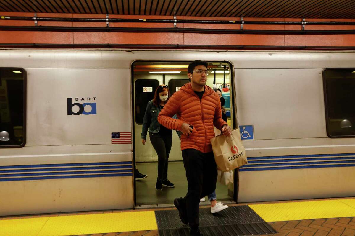 An unmasked and masked passengers disembark from a train at San Francisco’s Powell Street BART station in April. The rail system will offer discount rides in September, to honor its 50th anniversary.