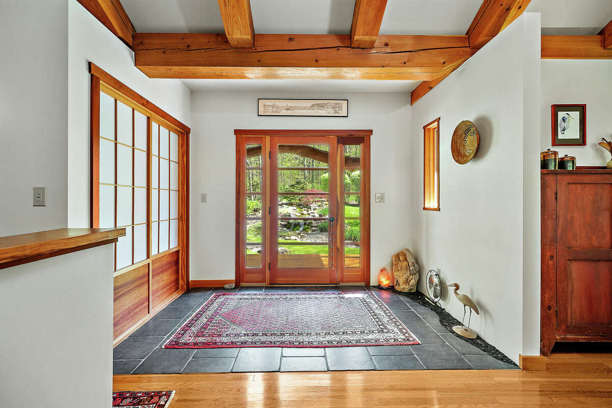 This week’s house is a Japanese-inspired timber frame design on 52.88 acres in Rensselaerville. The house, built in 2006 at 115 Littner Road, has 2,500 square feet of living space on two levels and its private setting in the woods suggests a peaceful, quiet atmosphere. The layout on the first floor is open and cherry trees harvested on the property were included in the support structure. The main living space has a timbered, cathedral ceiling. There are two bedrooms and two and a half bathrooms. Outside, the landscaping includes a 26-foot stream and waterfall.  There is also a cabin and a garage on the property. The cabin, 14-feet by 22-feet, is on the edge of the pond and includes a deck built around a living tree. The garage is 24-feet by 40-feet has three bays, storage and work space. Taxes after exemptions: $10,893. Greenville schools. List price: $890,000. Contact listing agent Hans Soderquist at Cornerpin Realty at 518-336-0125.