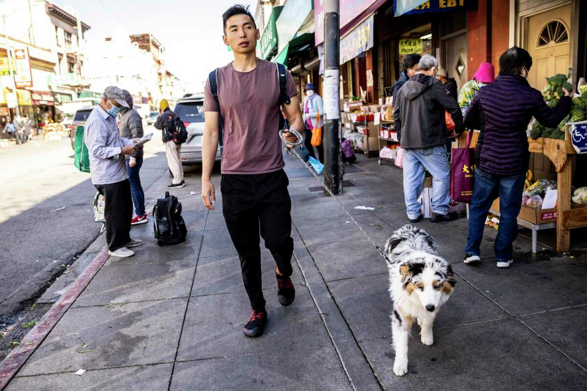 Justin Zhu, co-founder and executive director of Stand with Asian Americans, walks with his dog Bacca along Stockton Street in Chinatown.