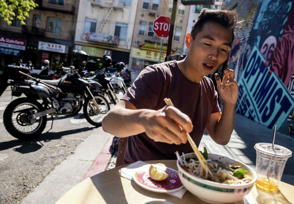 Justin Zhu, co-founder and executive director of Stand with Asian Americans, takes a phone call during lunch in Chinatown. The March 2021 killing of six Asian woman in the Atlanta area galvanized him.