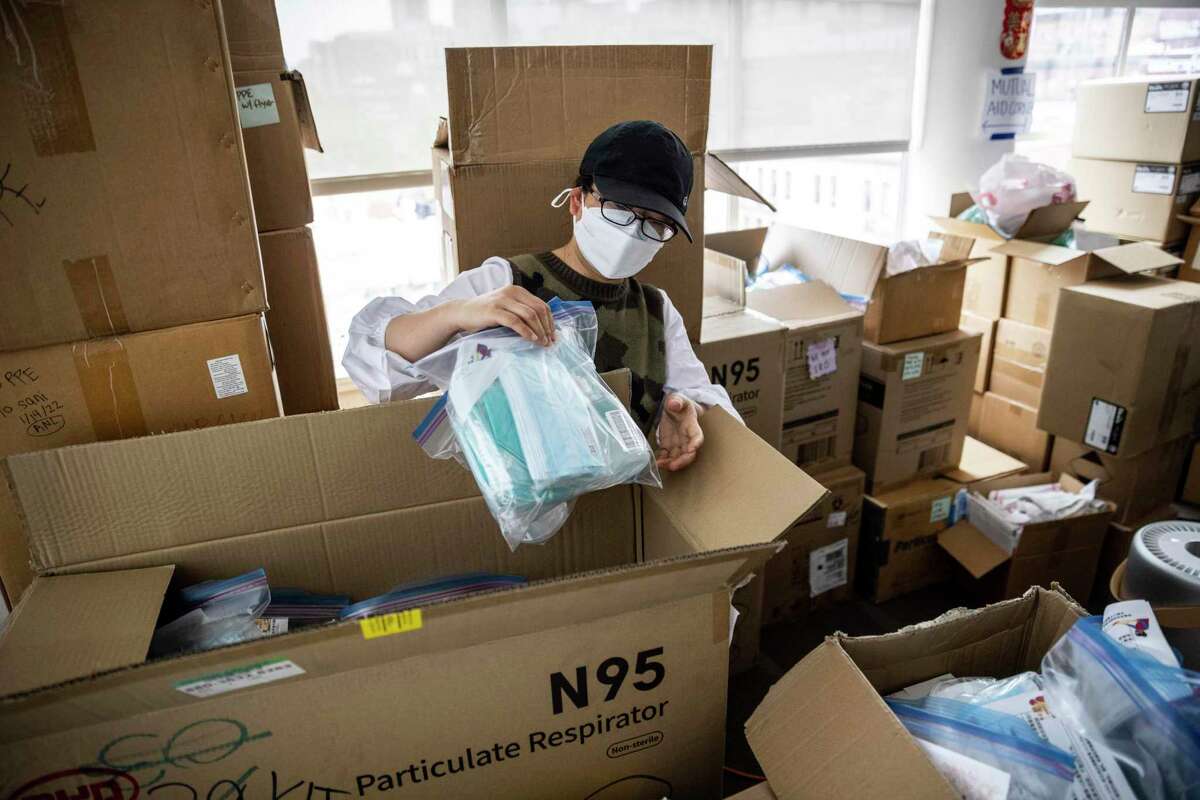 Yulian Luo, a community organizer with the Chinese Progressive Association, checks a package of personal protective equipment for SRO residents.