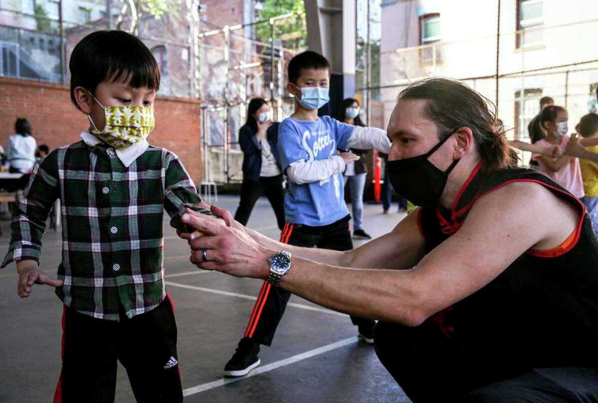 Martial arts instructor Justin Hoover teaches 4-year-old Haoran Huang how to make a fist during a class in Chinatown.