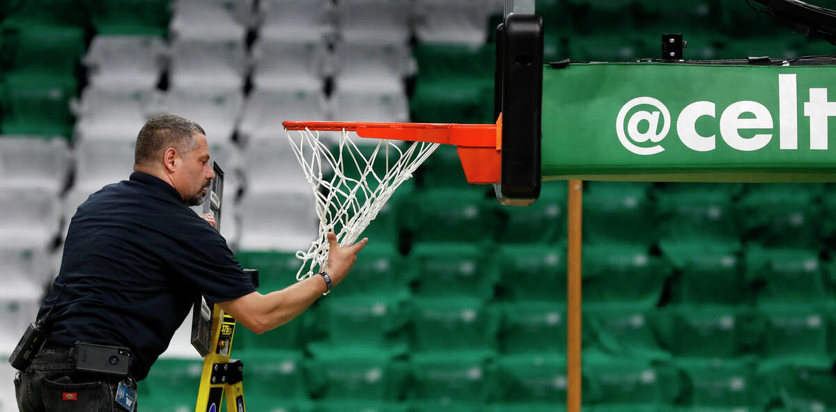 A worker was checking the level of the basket and the net on a ladder before the game. The Boston Celtics hosted the Golden State Warriors for Game Three of the NBA Finals at the TD Garden. (Jim Davis/The Boston Globe).