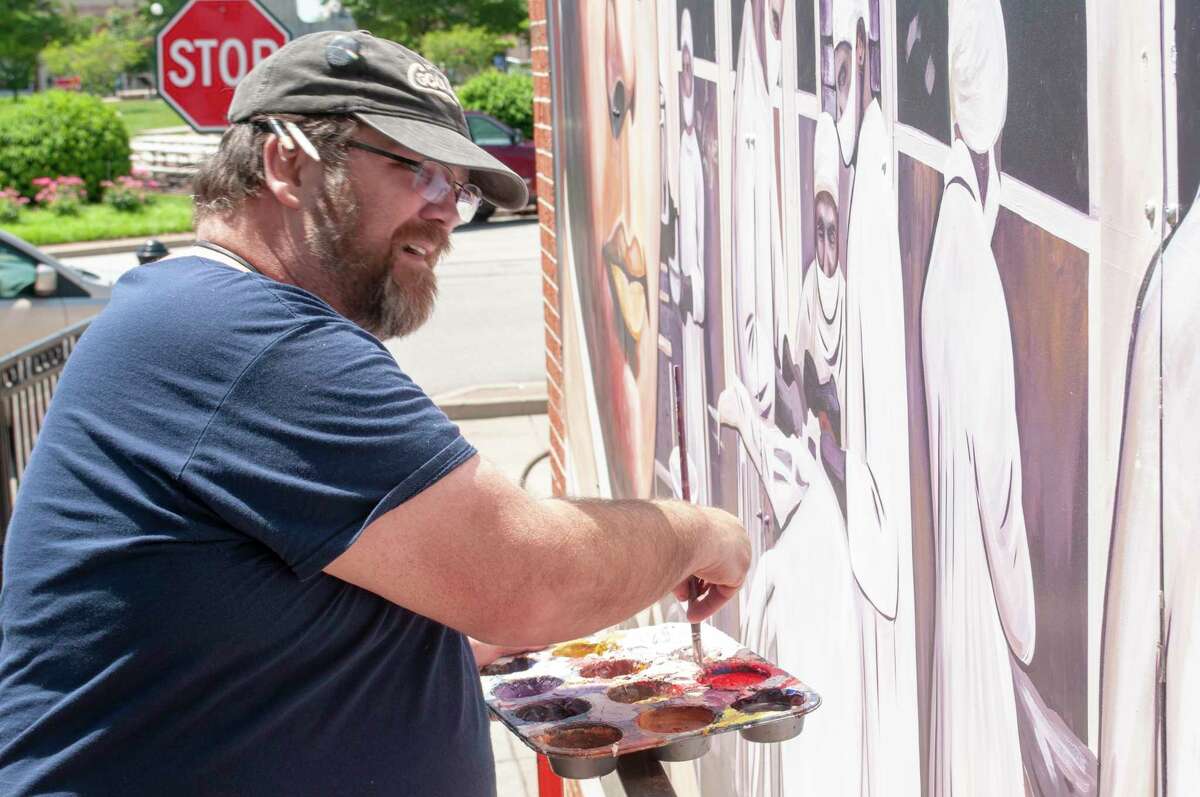Wall Dog community member Scott Lindley works Thursday to touch up part of the Dr. Alonzo Kenniebrew mural on the east wall of Lincoln Land Community College in downtown Jacksonville. 