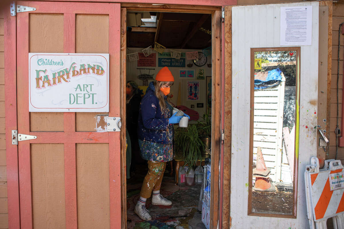 Children's Fairyland director of art and restoration Shannon Taylor (in orange cap) carries some canisters of molding clay in the art department's workspace in Oakland, Calif., on June 8, 2022. There, she helps restore and keep the theme park's rides and attractions in tip-top shape.