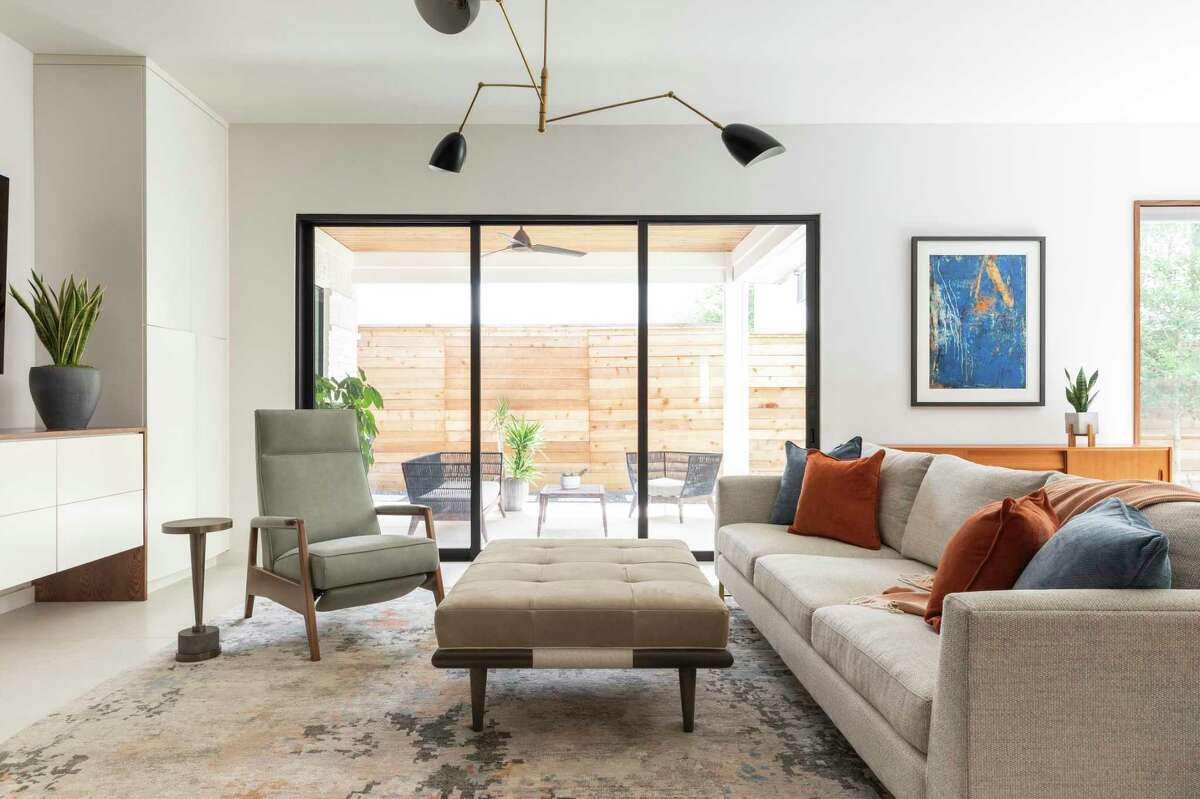 The living room is largely light neutral with muted blue and orange in pillows, the rug and artwork.