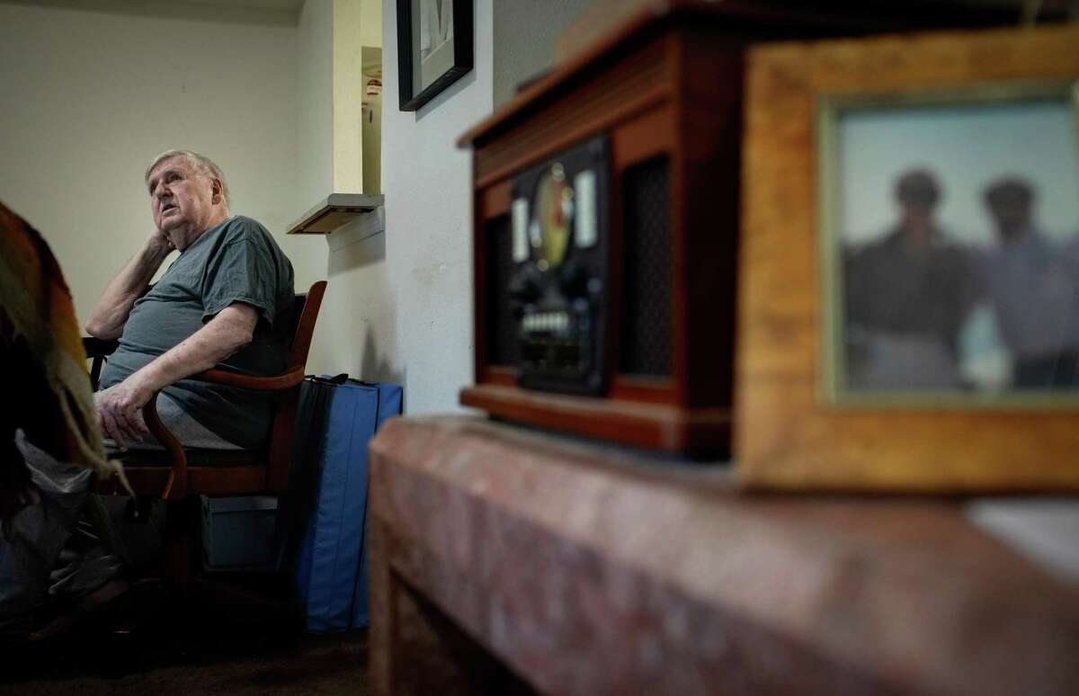 Larry Lingle, 85, talks about his life Thursday, June 9, 2022, at his apartment in Allen Parkway Village in Houston. Behind Lingle is a photo of his late partner, Bill White, who died in 1995 from complications from AIDS.