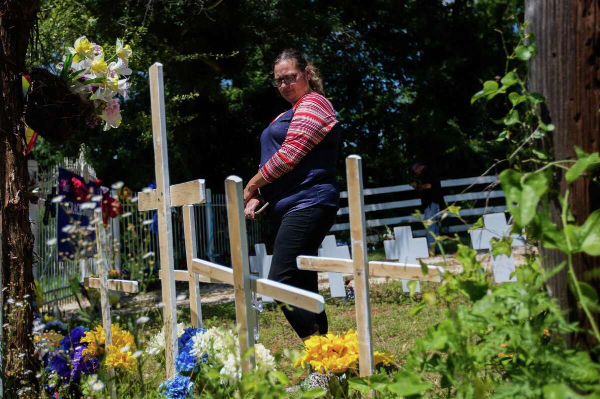 Diana Martin, a resident of Marquez, takes a look at the flowers and comforting items placed at a makeshift memorial, Tuesday, June 7, 2022, at the site where members of the Collins family were killed by a fugitive in Centerville.