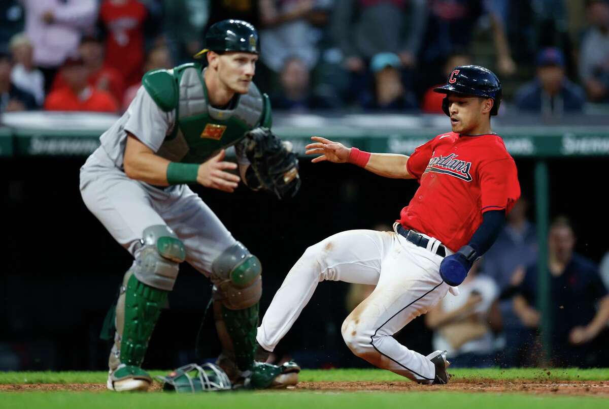 The Guardians’ Steven Kwan slides into the plate behind A’s catcher Sean Murphy, scoring on a single by Oscar Gonzalez during the sixth inning in Cleveland.