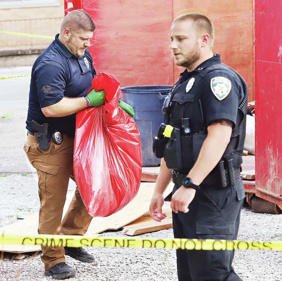 John Badman|The Telegraph An Alton Police detective carries one of three large bags of evidence collected from the dumpster to a state police vehicle.
