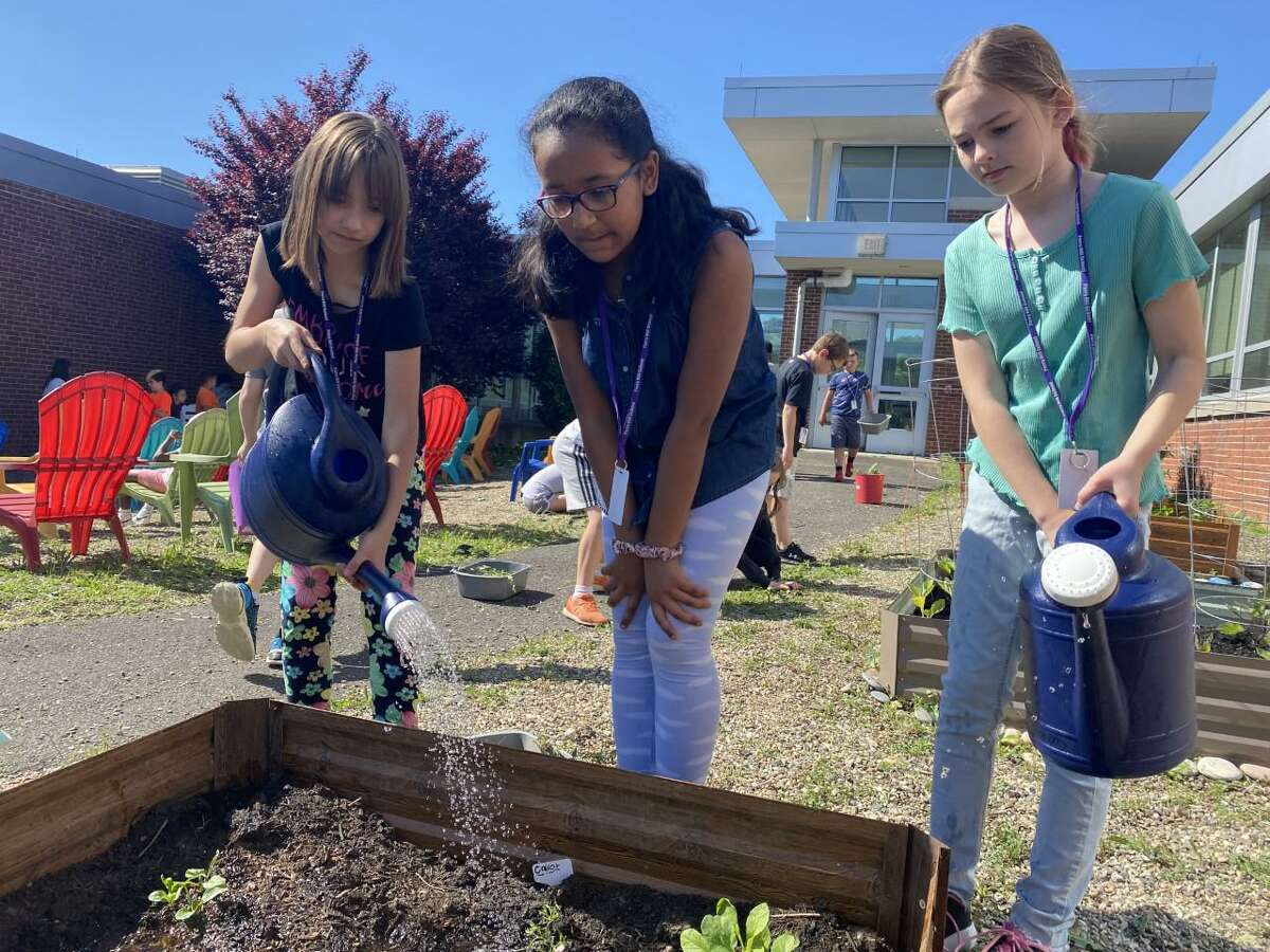 Perry Hill School students water plants and weed gardens in the school’s outdoor classroom.