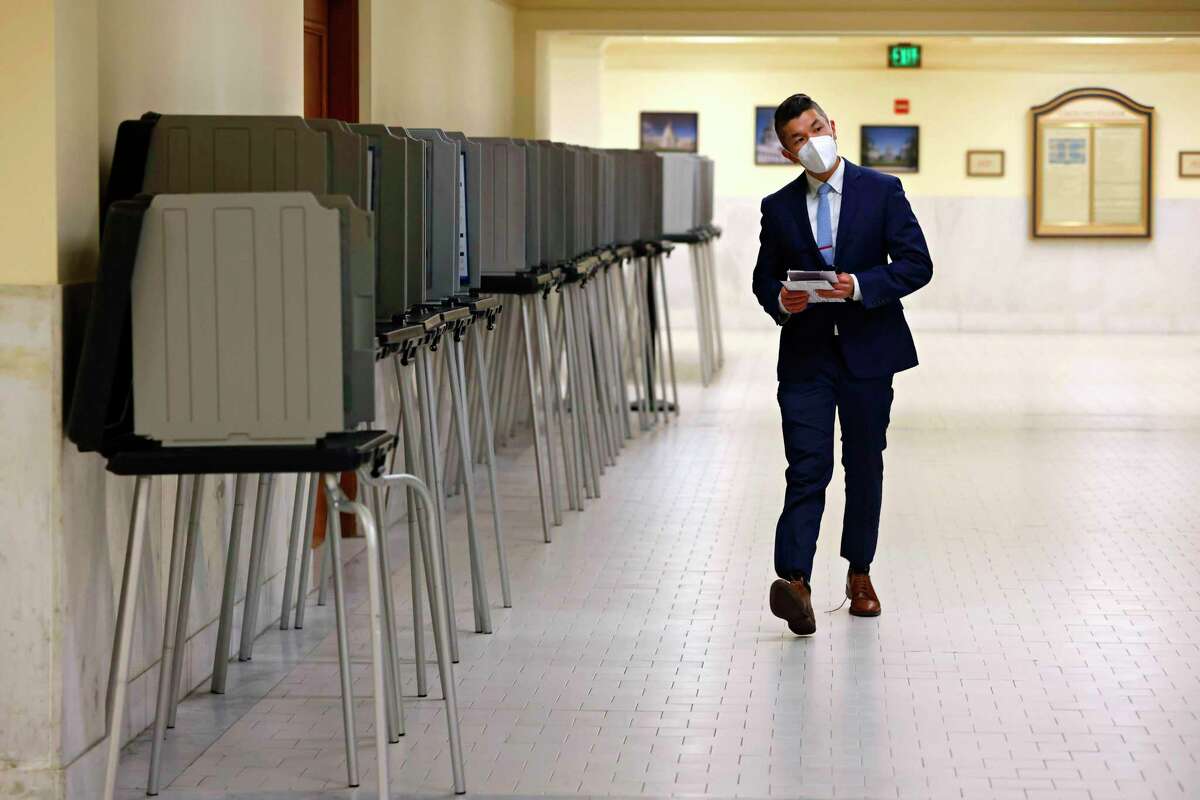 Binh Tran carries his ballot past empty voting booths as he looks for a drop box at San Francisco City Hall on Tuesday.