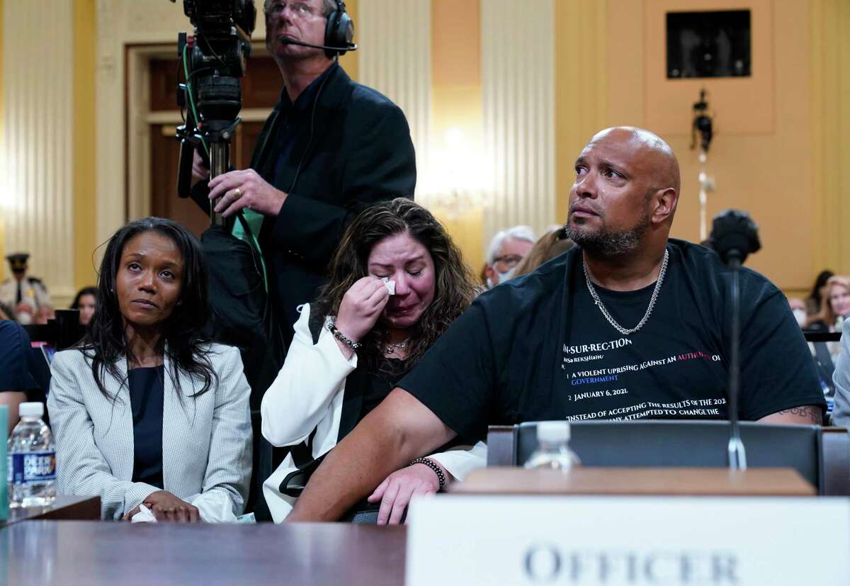 U.S. Capitol Police Sgt. Harry Dunn, right, consoles Sandra Garza, the long-time partner of fallen Capitol Police Officer Brian Sicknick, center, as a video of the Jan. 6 attack on the U.S. Capitol is played during a public hearing of the House select committee investigating the attack is held on Capitol Hill, Thursday, June 9, 2022, in Washington. Serena Liebengood, widow of Capitol Police officer Howie Liebengood, reacts at left. (AP Photo/Andrew Harnik)
