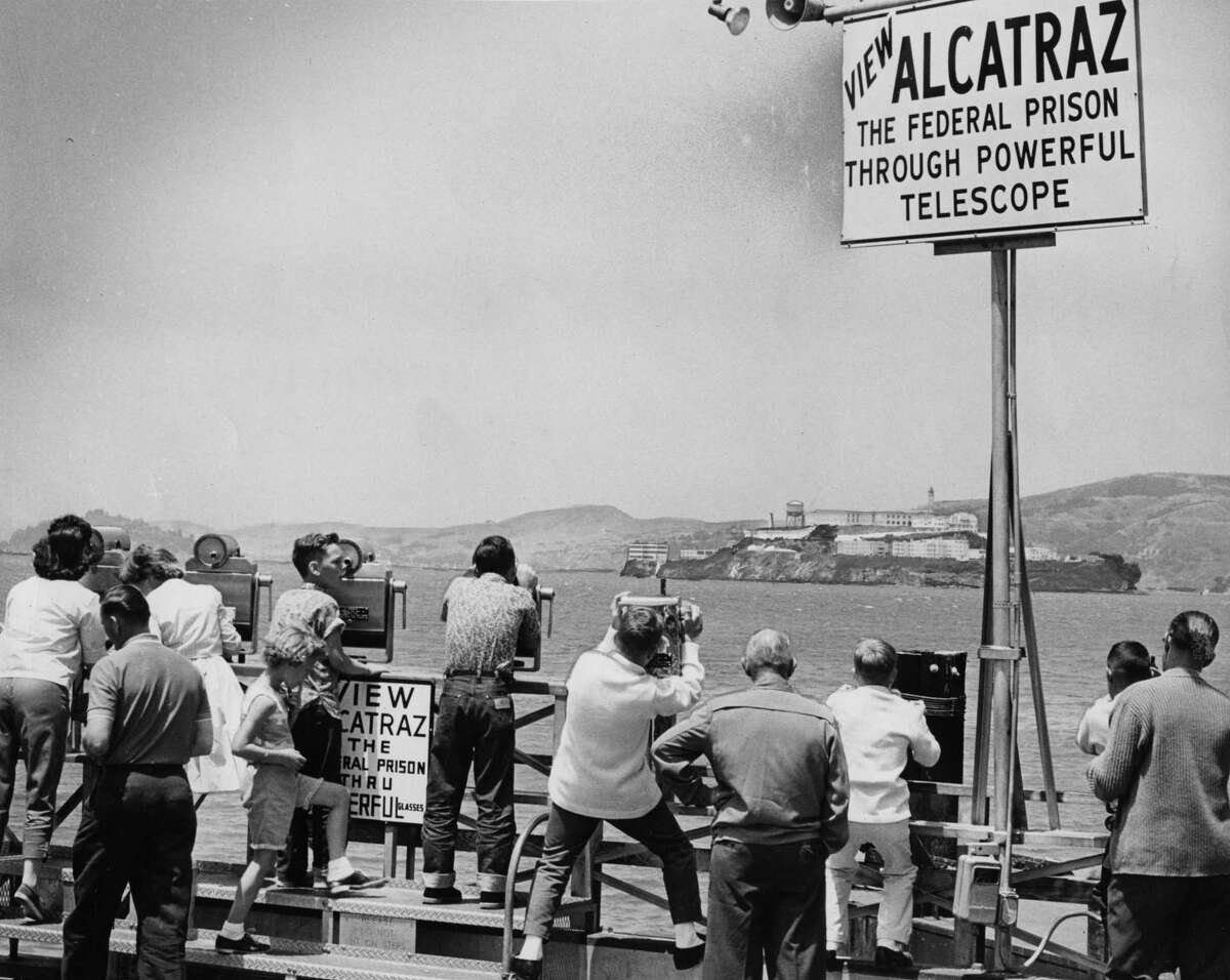 People looking through a telescope at Alcatraz Federal Penitentiary after the trio escaped.