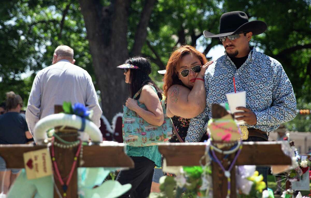 Claudia Carrizales leans onto her husband, Justin Carrizales, while they spend time by the memorial crosses representing the 21 victims of the Uvalde massacre Sunday, June 5, 2022, at townsquare in Uvalde. A Texas House committee formed to investigate last month’s massacre at Robb Elementary School will meet Thursday and Friday at the Uvalde city hall to hear testimony from law enforcement authorities.