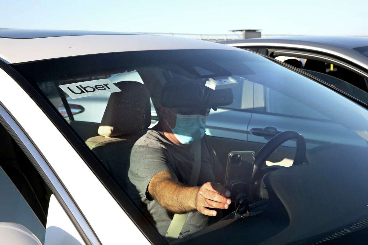 From a staging area, Uber driver Omer Iltas, 43, of San Mateo, prepares to pick up a customer at the San Francisco International Airport on Wednesday, August 12, 2020, in San Francisco, Calif.