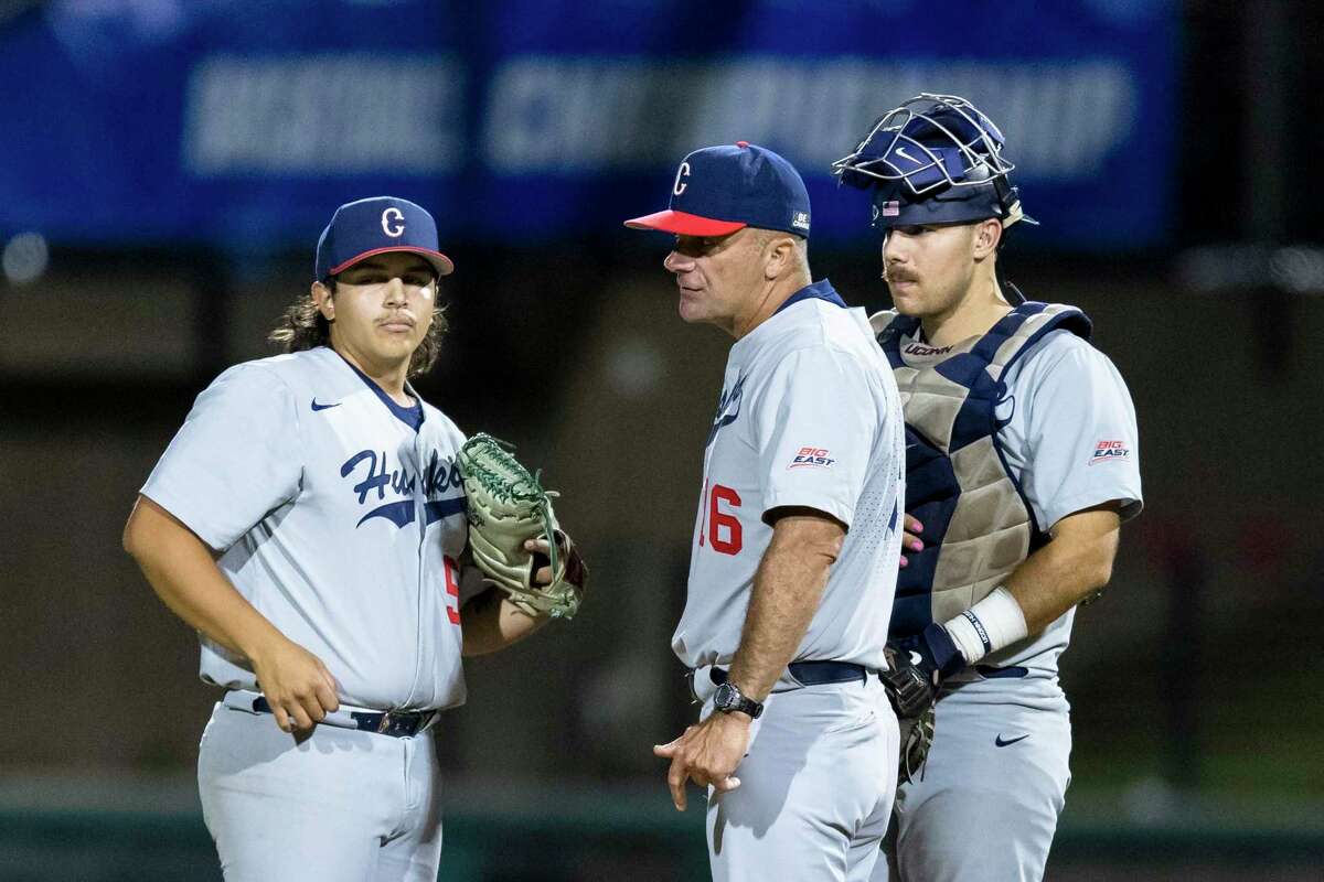 Connecticut head coach Jim Penders, middle talks to pitcher Devin Kirby, left, and Matt Donlan, right, during the ninth inning of an NCAA college baseball tournament super regional game Saturday, June 11, 2022, in Stanford, Calif. Connecticut won 13-12. (AP Photo/John Hefti)