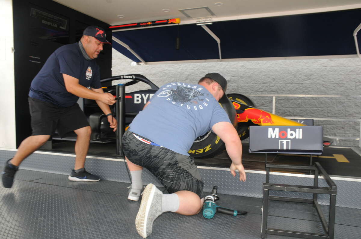 Robert Bland, right, gets ready use the impact wrench to secure a tire as he breaks the eight-second barrier on Saturday during the Red Bull Pit Stop Challenge in Collinsville.