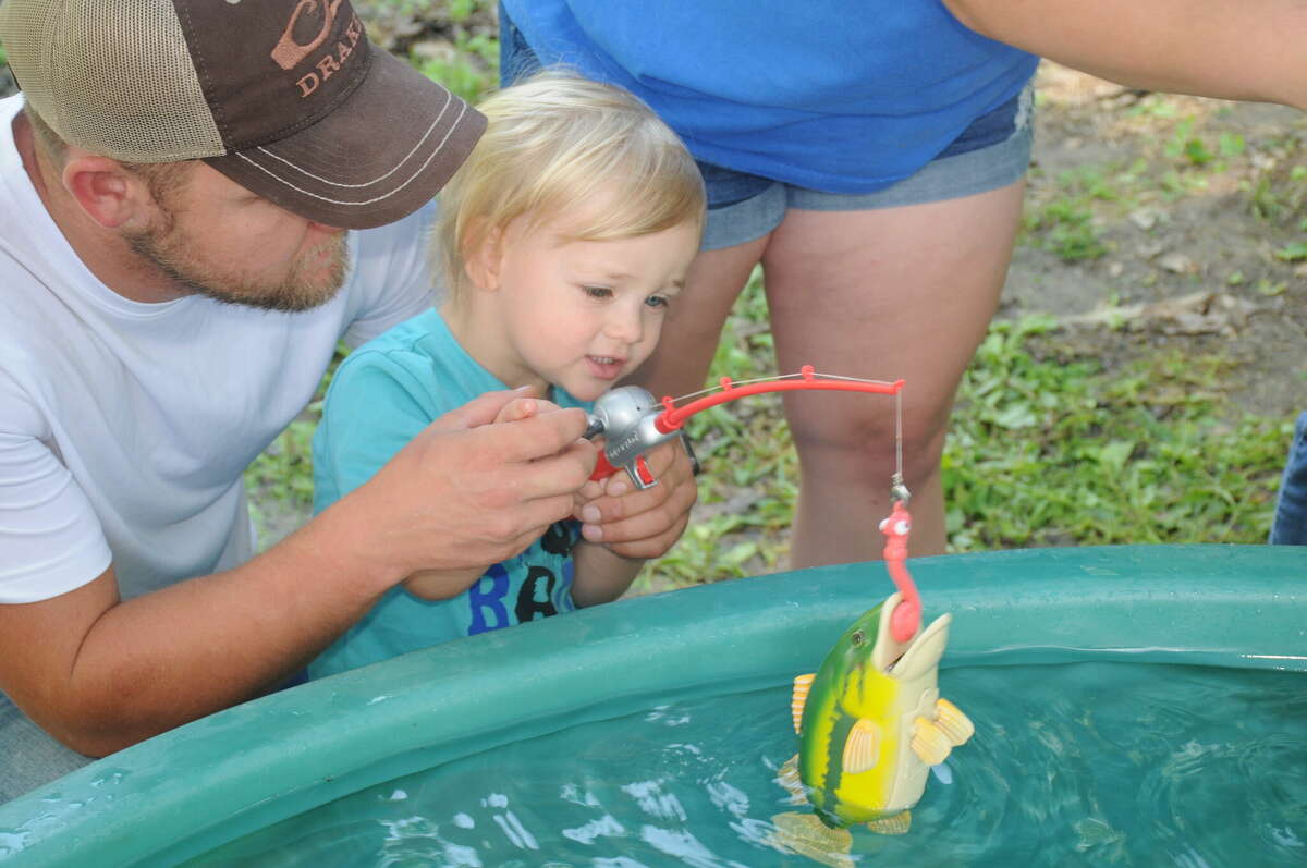 Ryan Poirrer helps his two-year-old son Greyson hook a toy fish at the kiddie fishing pool on Saturday at Pere Marquette State Park. 