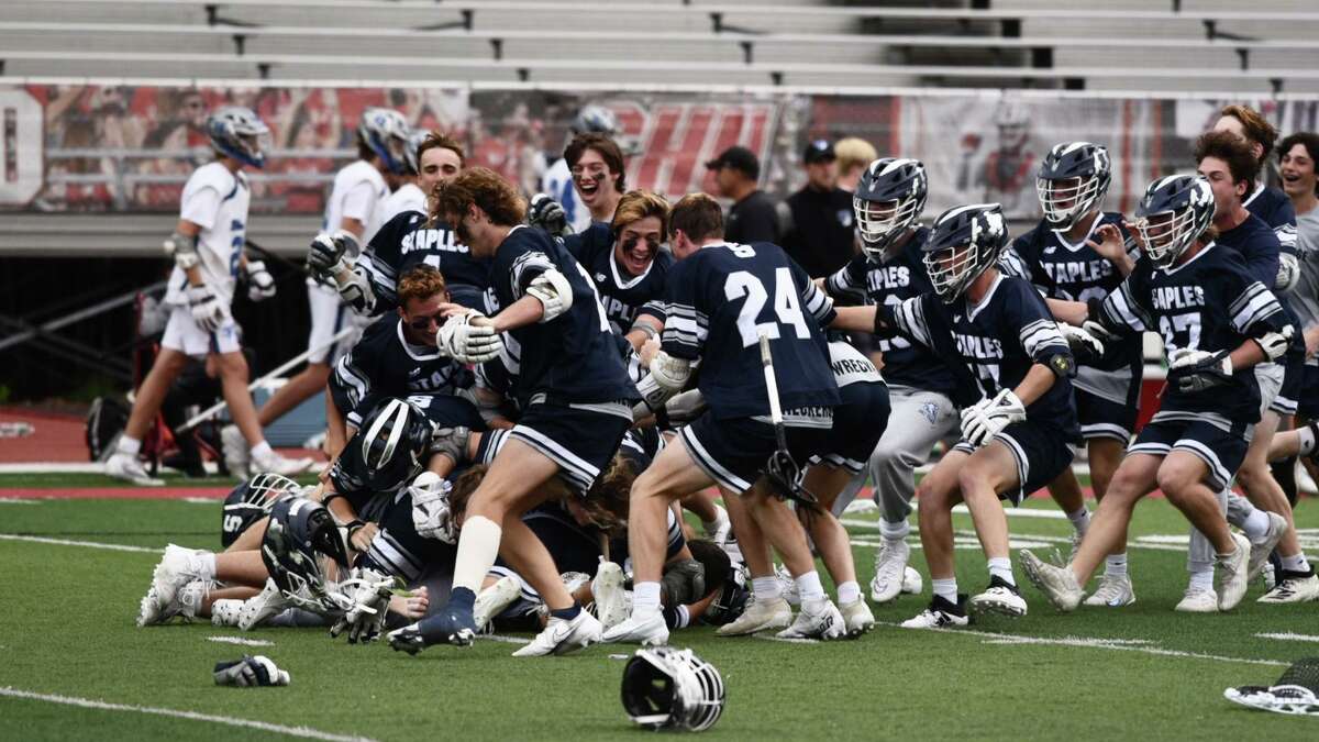 Members of the Staples boys lacrosse team celebrate following their 12-3 victory over top-seeded Darien in the CIAC Class L championship Sunday at Sacred Heart University.