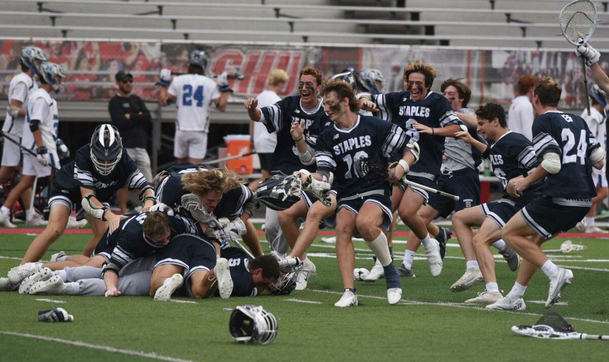 Members of the Staples boys lacrosse team celebrate following their 12-3 victory over top-seeded Darien in the CIAC Class L championship Sunday at Sacred Heart University.