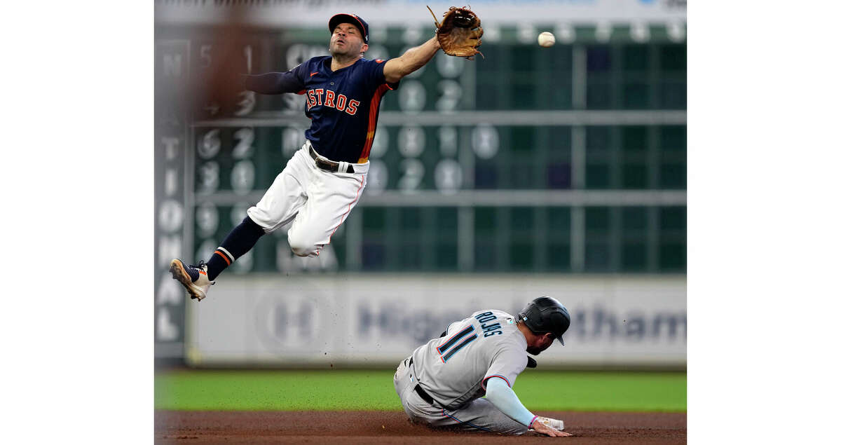Houston Astros second baseman Jose Altuve, left, reaches for the throw from catcher Jason Castro as Miami Marlins' Miguel Rojas (11) steals second base during the fourth inning of a baseball game Sunday, June 12, 2022, in Houston. Rojas advanced to third on the throwing error by Castro. (AP Photo/David J. Phillip)