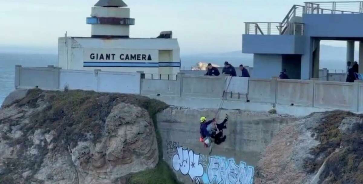 San Francisco firefighters rescue a man who climbed down the wall near the Cliff House, an image from Fire Department video.