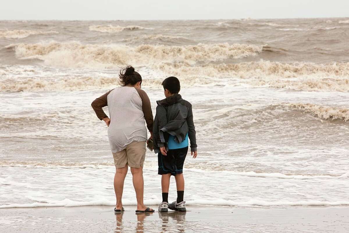Roberta Whitehat, of Arizona, with her son Dylan watch the surf in the aftermath of Tropical Storm Cindy in Cameron, Louisiana, on June 22, 2017. At least one death was blamed on Tropical Storm Cindy as it made landfall on US soil in the Gulf of Mexico on Thursday. The Miami-based National Hurricane Center reported that Cindy hit the coast of southwestern Louisiana and eastern Texas at around 0900 GMT, packing winds nearing 40 miles (65 kilometers) per hour. / AFP PHOTO / Daniel KRAMER (Photo credit should read DANIEL KRAMER/AFP via Getty Images)
