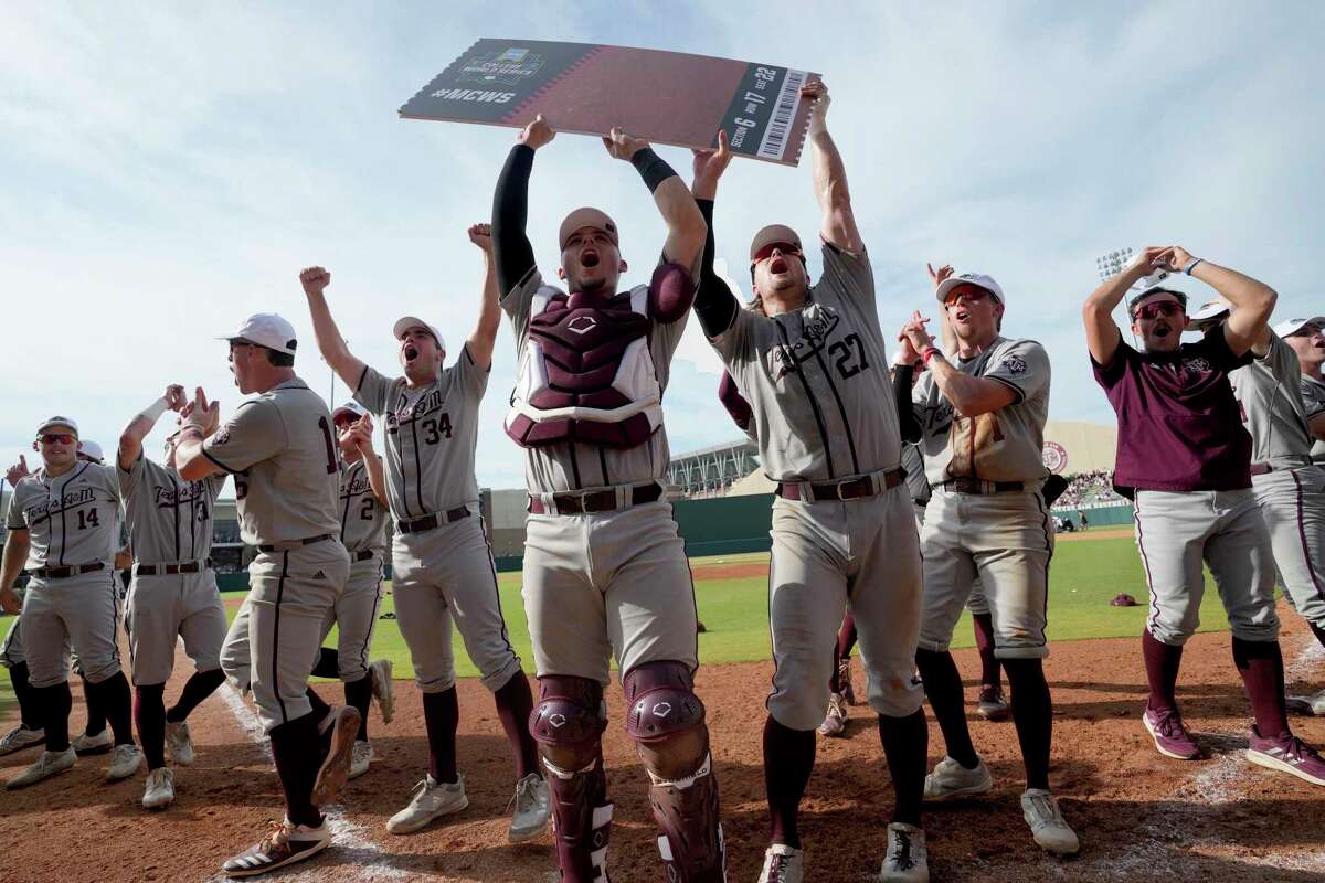 Texas A&M’s Troy Claunch, center, and Dylan Rock hold up a “Ticket to Omaha” sign.