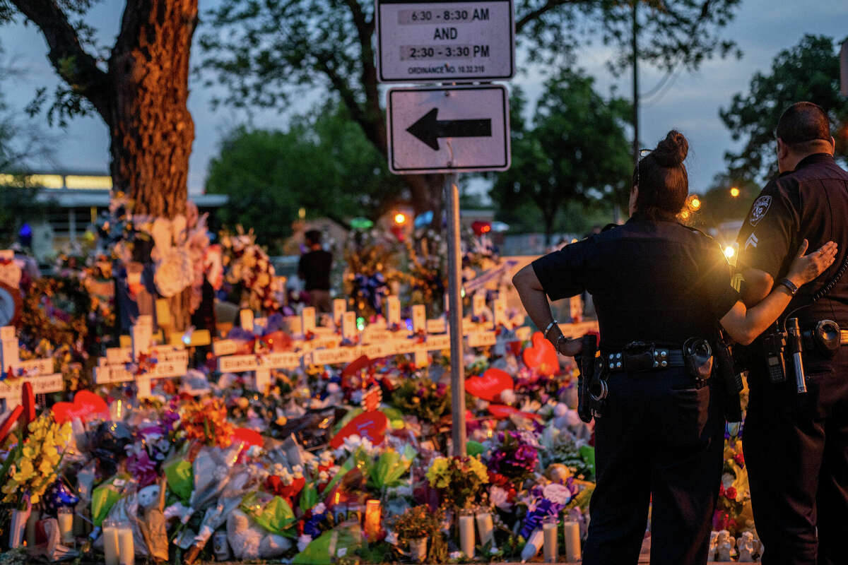 Police officers stand together at a memorial dedicated to the 19 children and two adults killed on May 24th during the mass shooting at Robb Elementary School on May 31in Uvalde, Texas.