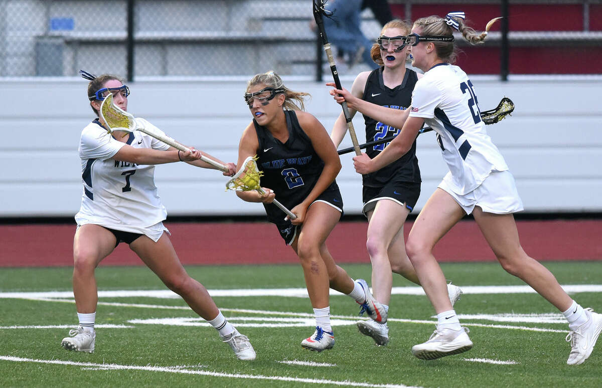 Darien's Chloe Humphrey (2) cuts between Wilton's Morgan Breakey (7) and Ashleigh Masterson (26) during the Class L girls lacrosse semifinals in Greenwich on Tuesday, June 7, 2022.