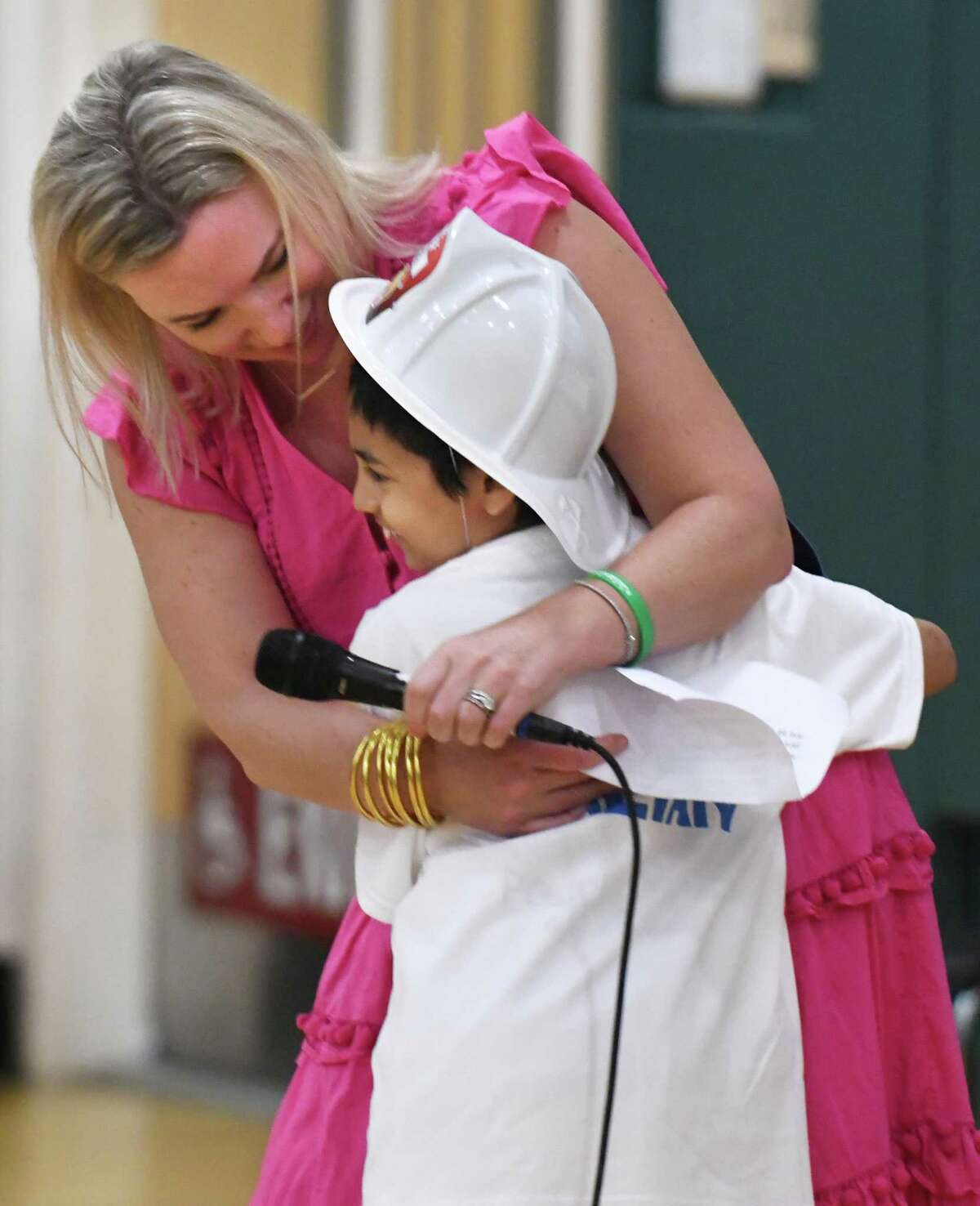 Principal Klara Monaco hugs third-grader Julian McRandal during an assembly at Glenville School in the Glenville section of Greenwich, Conn. Tuesday, June 14, 2022. McRandal, who has brain cancer, was surprised Tuesday morning to be driven to school in a fire truck with a police motorcycle motorcade. The entire school was waiting outside to greet him, give him gifts, and honor him during a school assembly.